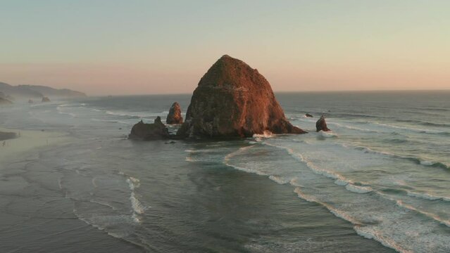 Low circling aerial shot over Haystack rock at sunset