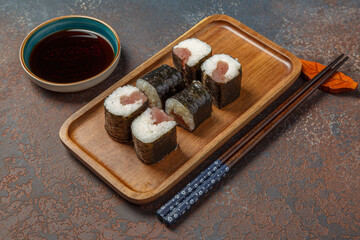 Maki au thon- spécialité culinaire japonaise - sur une assiette en bois avec une sauce soja et baguettes.