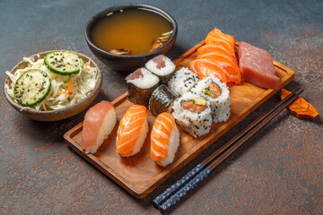 Menu de sushi, maki et California rolls sur une planche en bois servie avec une soupe miso et...
