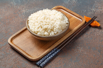 Bol de riz nature sur un plateau avec une sauje soja et baguettes. 