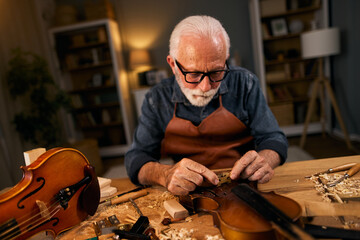 Senior carpenter craftsman carving wood and making violin instrument