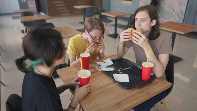 group of students sit in a cafe and have breakfast together. business concept of modern training and lifestyle development. students discuss homework and eat fast food burgers talk about project