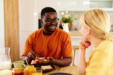 Fototapeta na wymiar Multiracial couple enjoying breakfast together at home
