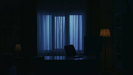 Focus on the empty desk with pc monitor and keyboard in the dark apartment living room. Everyday life creative concept.