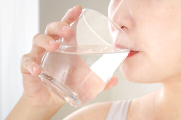 グラスのお水を飲む若い女性