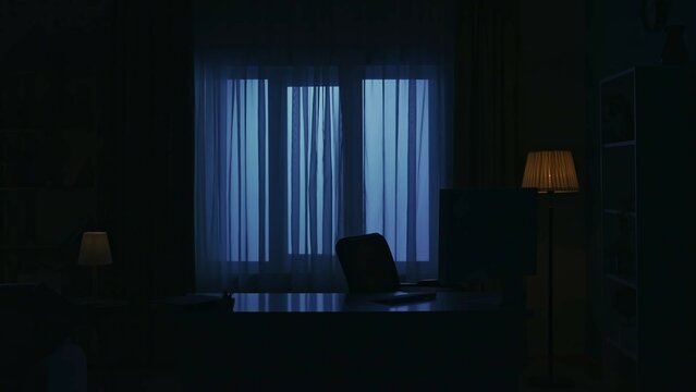 Focus on the empty desk with pc monitor and keyboard in the dark apartment living room. Everyday life creative concept.