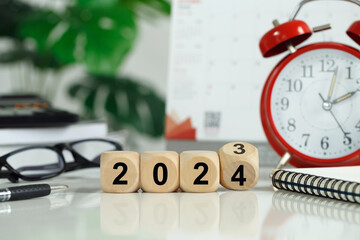 Flipping wooden block cubes from 2023 to 2024 on the desk.Christmas and Happy New Year.business...