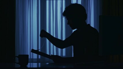 Everyday life creative concept. Man at the desk in the dark room working, reading paper documents.