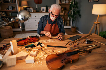 Senior carpenter craftsman carving wood and making violin instrument © Stockphotodirectors