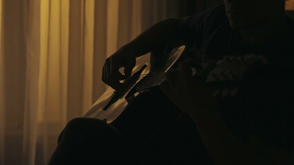 Closeup shot of a man hands playing melody on the acoustic guitar. Everyday life creative concept.