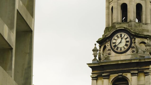 historic round clock tower building with roman numeral custom hand made numbers moving cinematic shot afternoon time located in London moody dramatic scenery