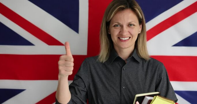 Young female supports language learning. Delighted English teacher stands in front of Union Jack British flag and encouragement of students to study
