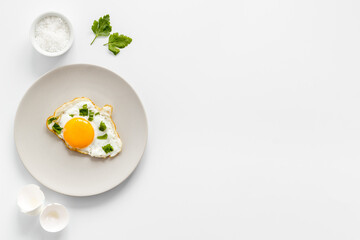 Cooking fried eggs with coriander, top view. Breakfasr background