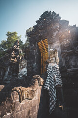 Porte traditionnelle entourée de statues au temple bouddhiste Goa Lawah, Bali. Indonésie.