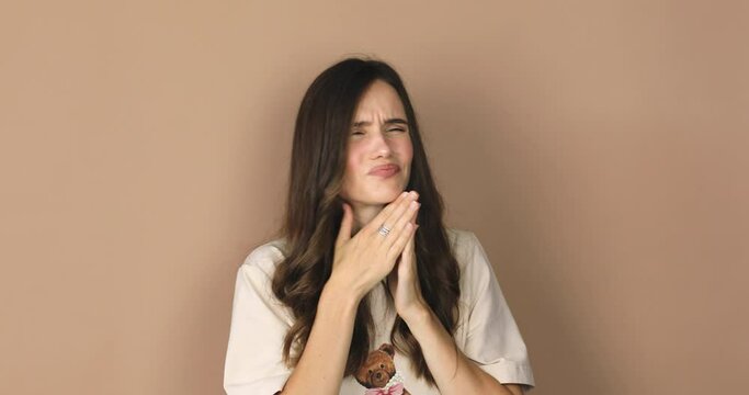 Woman wear beige t-shirt is suffering with cough and feeling bad on beige background. Health care and safety. Millennial woman coughing hardly while hold neck.