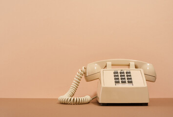 Beige phone with gray buttons on a beige background. Copy space for text. Retro style.