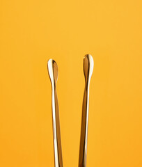 Metal ice tongs gold color for put ice in glasses with alcoholic beverages on a bright yellow background. Night club party.