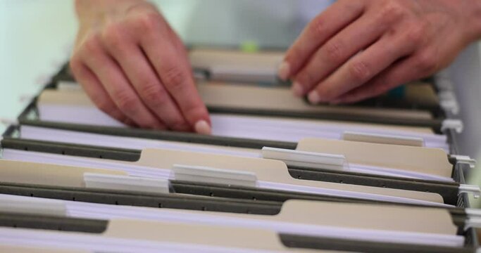 Worker organizing cardboard boxes containing files in company. Company documents stored on office shelves. Concept of business archive paperwork slow motion