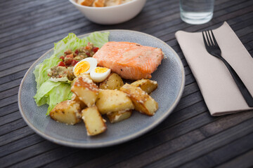 Baked salmon fillet with fried potato wedges, homemade guacamole and quail eggs halves