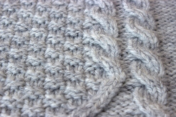 Texture of gray knitted sweater with braids