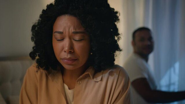 African American woman victim wife girlfriend crying scared afraid upset listening screaming man shouting angry mad aggressive husband yelling quarrel accused of cheating and treason at bed at night