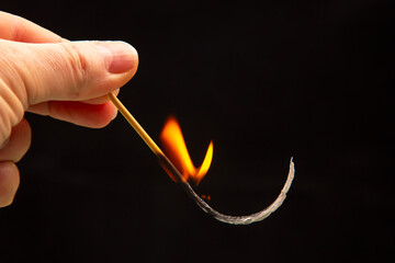 Fire and smoke. Burning match in hand on a black background. Heat and light from fire flame