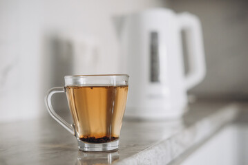 There is a white plastic teapot on the table together with a cup for brewing tea