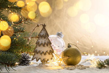 Christmas decorations on a snowy table with fir branches and glowing garlands. Copy space