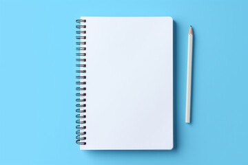A white notebook is next to white pencil on a blue background 