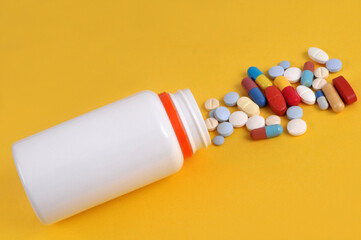 Assortiment de médicaments sortant d'un flacon en plastique blanc sur fond jaune