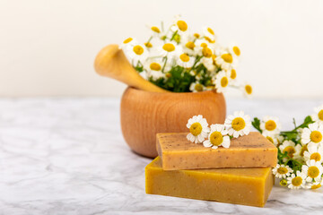 Fototapeta na wymiar Natural homemade soap with chamomile flowers on a wooden table. Close-up of moisturizing soap with natural herbal oils. Spa and beauty concept. Place for text. Copy space.Fletley