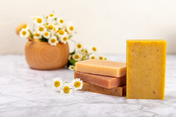 Natural homemade soap with chamomile flowers on a wooden table. Close-up of moisturizing soap with natural herbal oils. Spa and beauty concept. Place for text. Copy space.Fletley