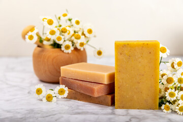 Natural homemade soap with chamomile flowers on a wooden table. Close-up of moisturizing soap with natural herbal oils. Spa and beauty concept. Place for text. Copy space.Fletley