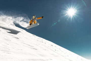 Real young snowboarder jumps and making trick from kicker at off piste ski slope. Winter vacations concept