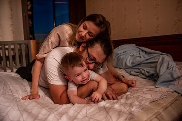 Happy young divesity caucasian family making human pyramid. Father with long hair, wearing glasses,...