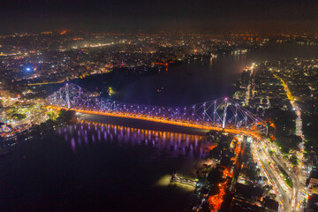 Aerial view of architectural landmark Howrah bridge or Rabindra Setu over the Hooghly River at night in Kolkata, West Bengal, India.