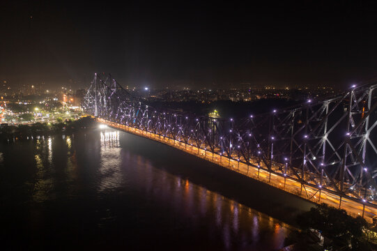 Aerial view of architectural landmark Howrah bridge or Rabindra Setu over the Hooghly River at night in Kolkata, West Bengal, India.