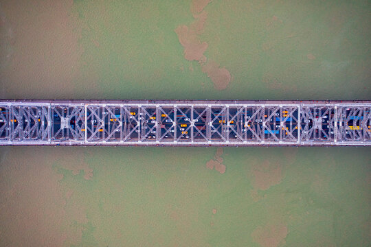 Aerial view of architectural landmark Howrah bridge or Rabindra Setu over the Hooghly River at day in Kolkata, West Bengal, India.