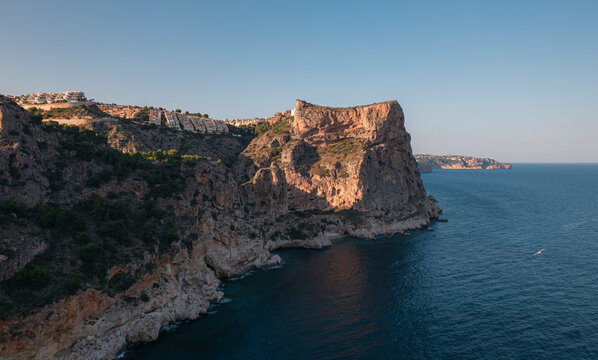 Aerial view of Breathtaking coastal panorama with clear blue sea, rugged cliffs, and the serene tranquility of small holiday houses, Cala Moraig, Zona Encinas, Cumbre del Sol, Alicante, Spain.