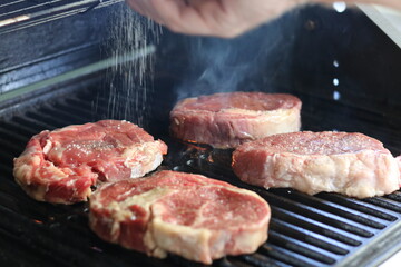 meat on the grill being seasoned