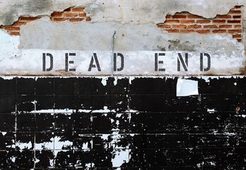 Old grunge ruined brick tiled wall with text inscription DEAD END, a road or a path with no exit at...