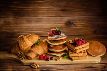 Fototapeta na wymiar Baking pancakes, croissants and waffles on a wooden background