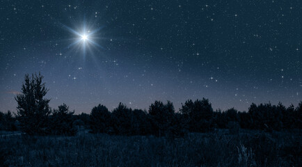 Bright star shines over the manger of christmas of Jesus Christ on blue starry sky - 647666623