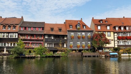 Fototapeta na wymiar A tranquil scene unfolds along the waterfront, where a row of buildings stands gracefully, reflecting off the gentle waves. Bamberg, Germany