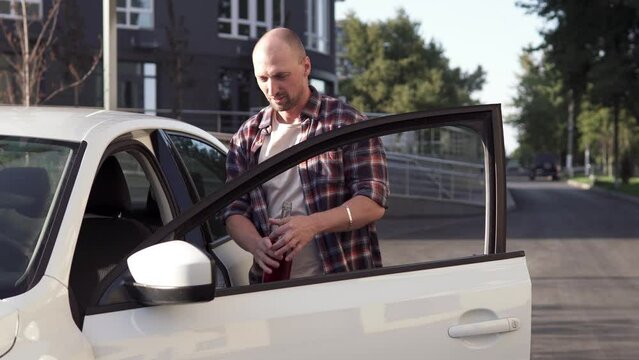 A depressed man gets behind the wheel of a car and drinks alcohol. The risk of driving while intoxicated. Car crash. Illegal drunk driving.