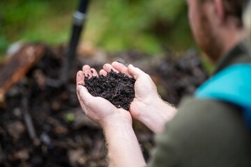 Farmer holding soil in there hands looking at soil health and taking a photo
