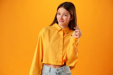 Gordijnen Photo of teen girl smiling portrait against yellow background in studio © fotofabrika