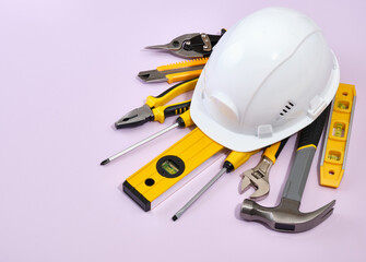 White head protection helmet and construction engineering tools. Hammer, screwdrivers, building level, yellow utility knife, pliers, adjustable spanner and clamps.