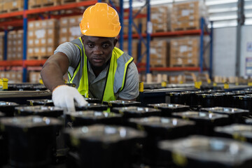 African American male warehouse worker wearing safety uniform using digital tablet inspecting...
