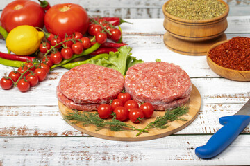 Raw hamburger patties on wood background. Raw veal hamburger patties with herbs and spices